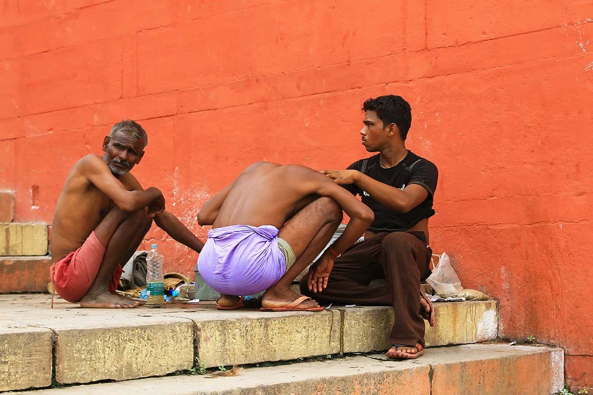 Man shaving his hair on the Ghats before taking a "holy dip" in the Ganges. Shaving the head before visiting the Ganges is thought to bring spiritual purification.